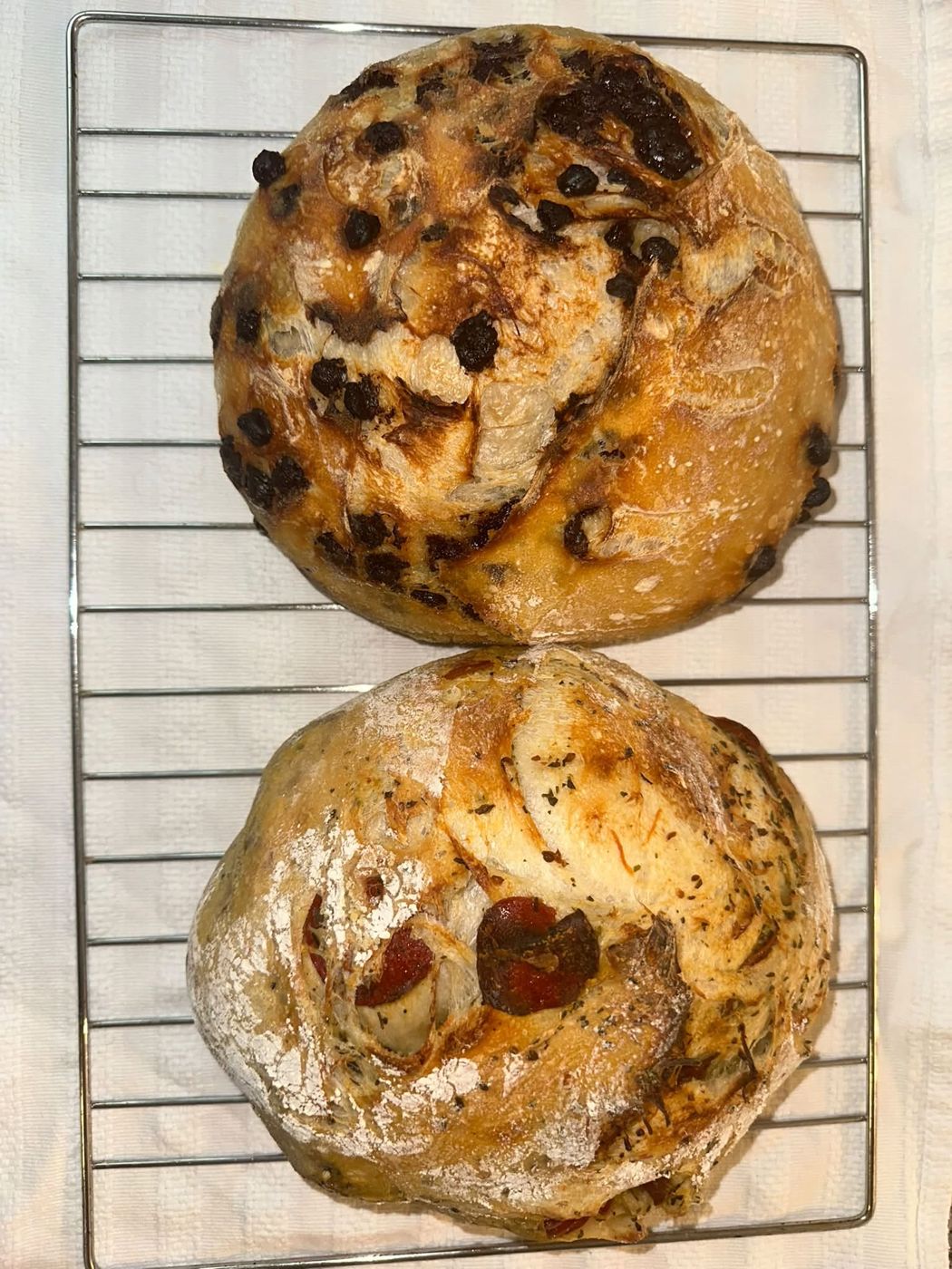 Two fresh sourdough loaves cooling on a wire rack